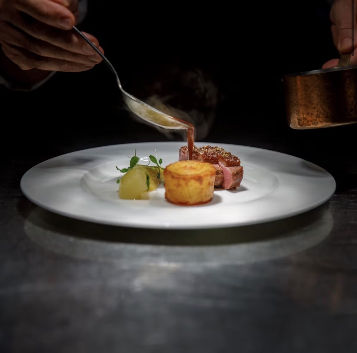 A chef finishing a plated dish